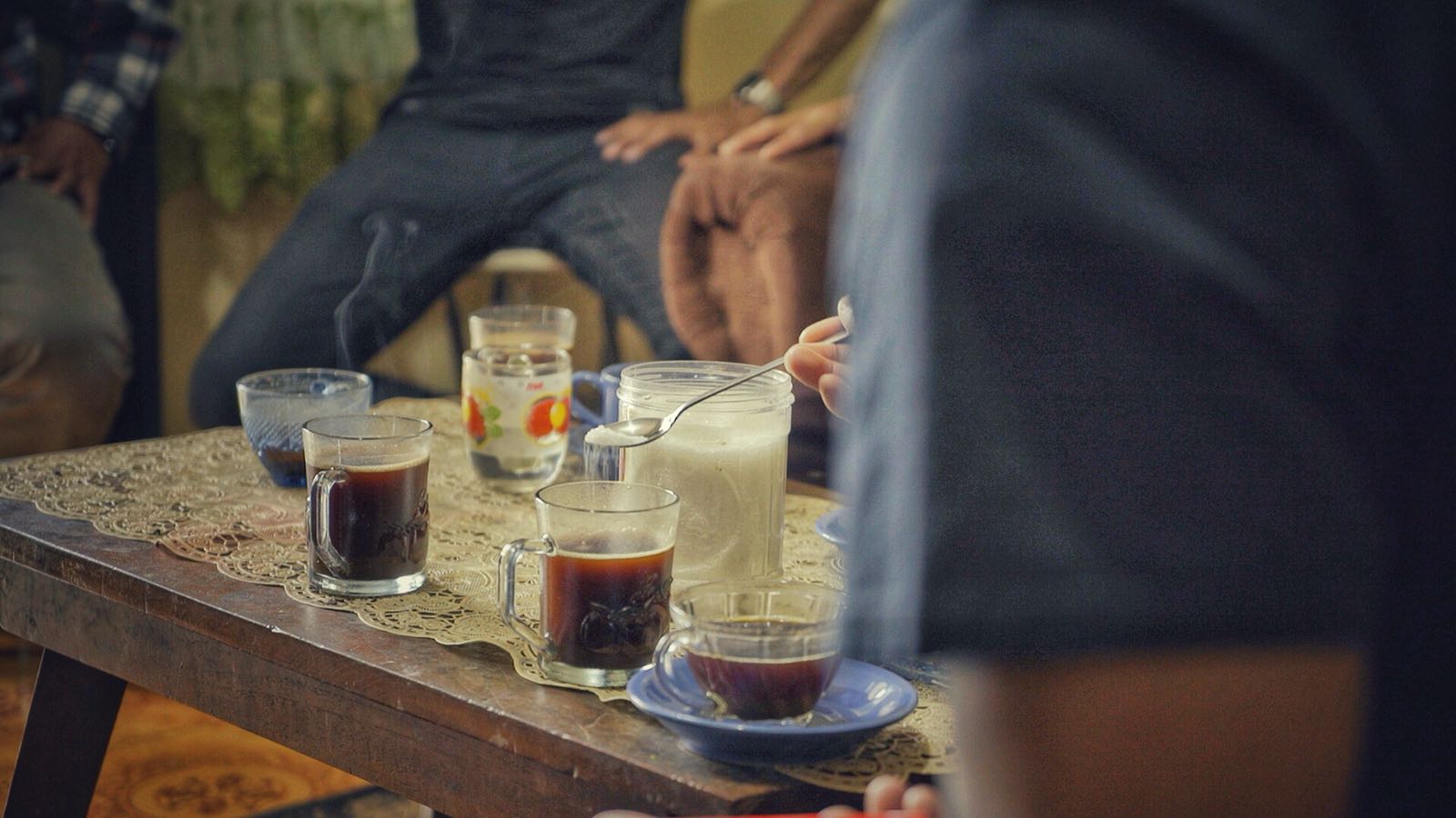 People sitting around a table with luwak coffee cups a casual setting