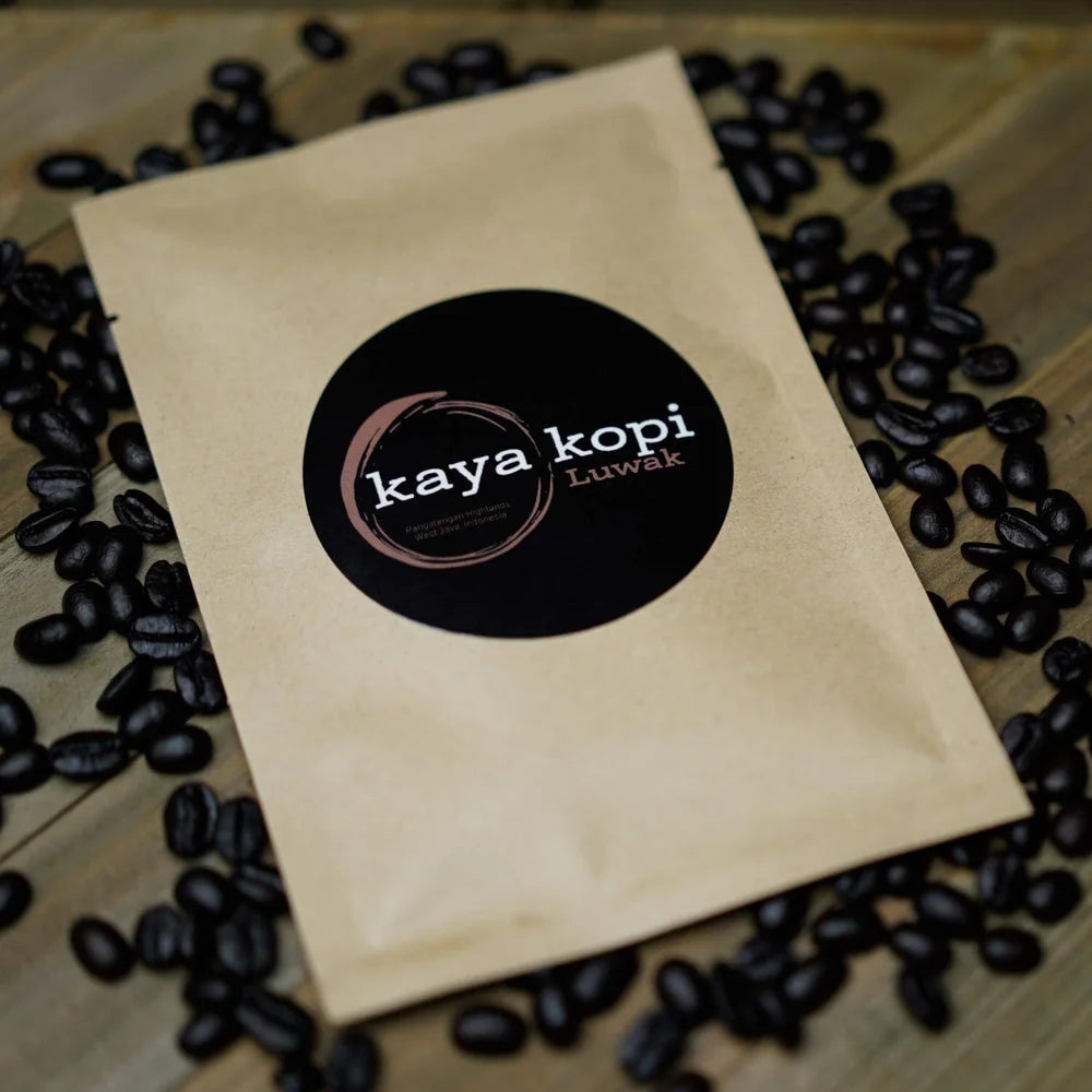 Kaya Kopi coffee package surrounded by coffee beans on a wooden surface