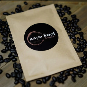 Kaya Kopi coffee package surrounded by coffee beans on a wooden surface