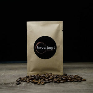 Kaya Kopi coffee package with coffee beans on a wooden surface