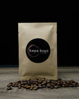 Kaya Kopi coffee package with coffee beans on a wooden surface