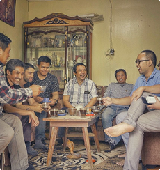 Group of men sitting around a table enjoying Luwak coffee in a cozy room.