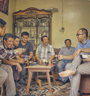 Group of men sitting around a table enjoying Luwak coffee in a cozy room.