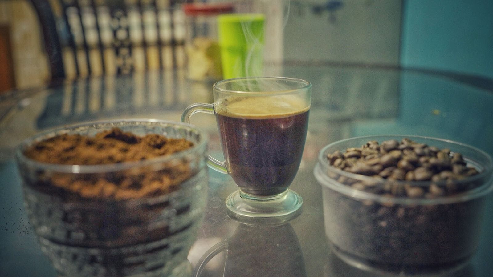 cup of luwak coffee, cookies, and luwak coffee beans on a reflective surface with a blurred background.