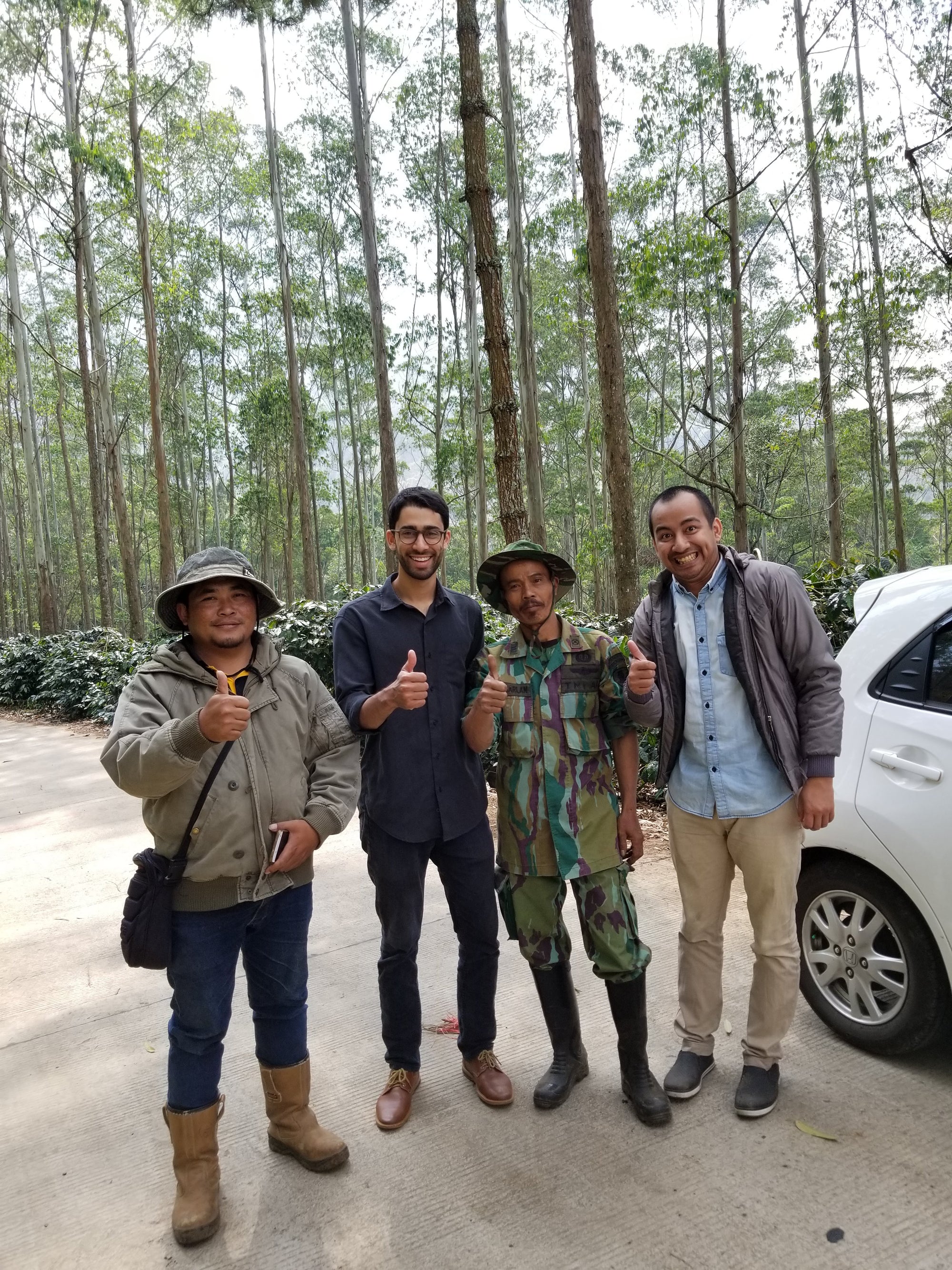 Group of people standing together on a rural road surrounded by trees, representing the story behind Kaya Kopi coffee.